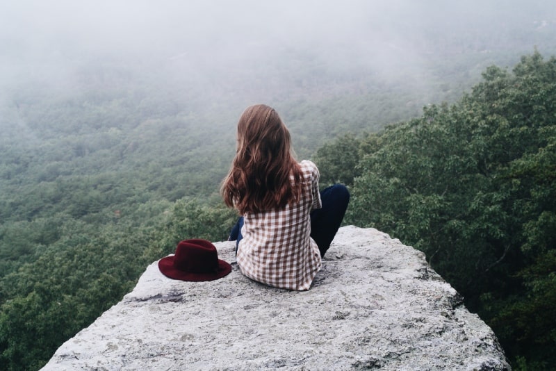 donna seduta sulla roccia vicino al cappello rosso