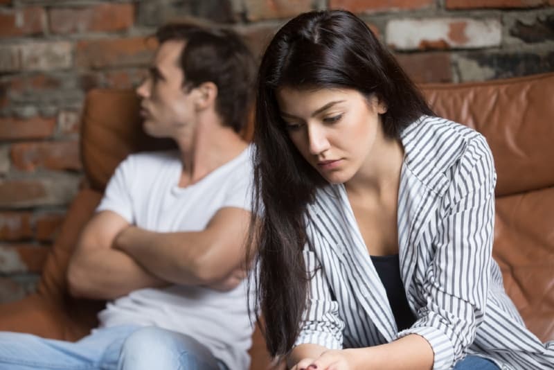 sad woman sitting on sofa near man