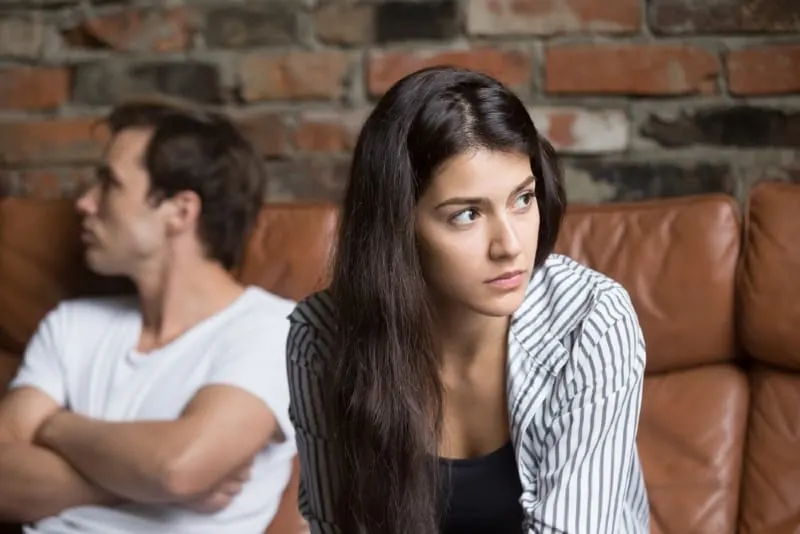 sad woman sitting on sofa near man