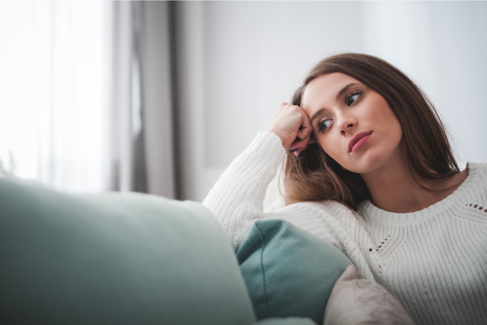 woman sitting on sofa at home deep in thoughts