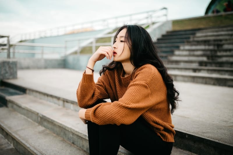 woman in brown sweater sitting on stairs