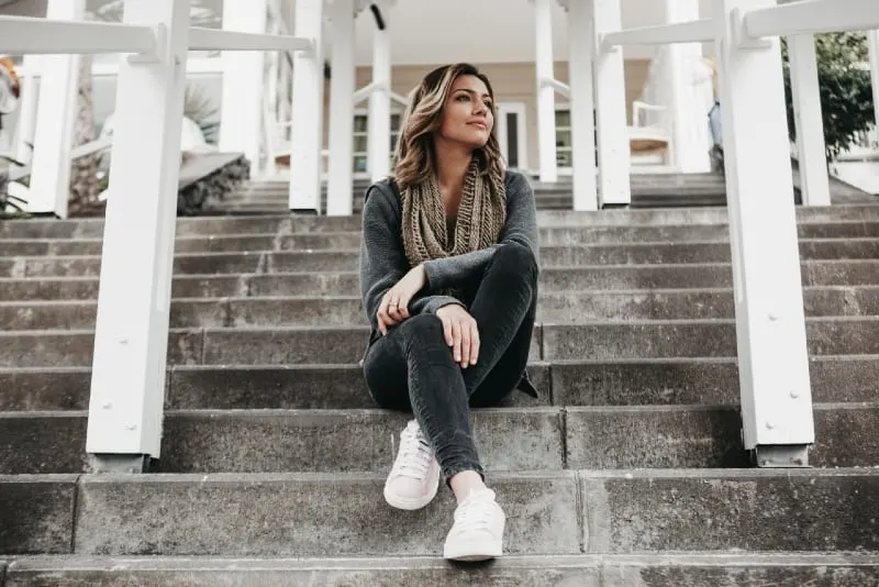 woman with gray scarf sitting on stairs