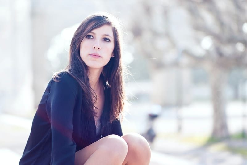 mujer con camisa negra sentada al aire libre