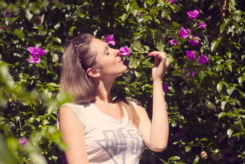 mujer oliendo flor morada