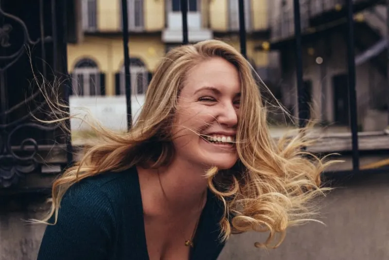 blonde woman smiling near wall outdoor