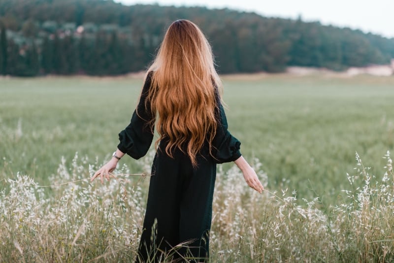 woman with long hair standing in the field