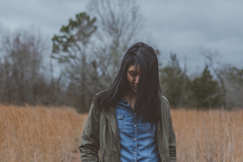 sad woman in gray jacket standing in the field