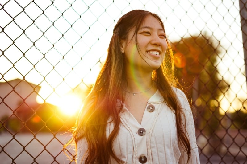 smiling woman standing near fence during golden hour