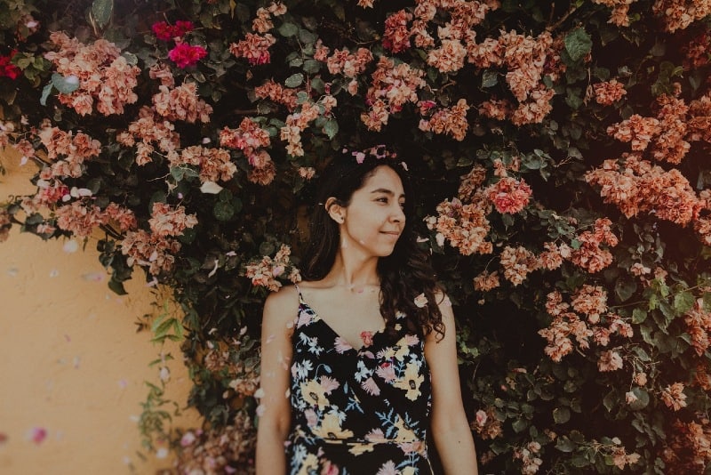 woman in floral dress standing near flowers