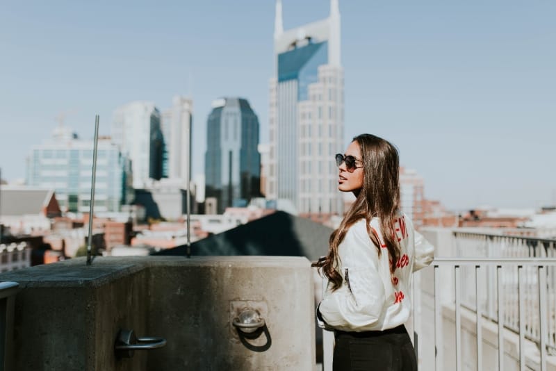 mujer con gafas de sol de pie cerca de las barandillas