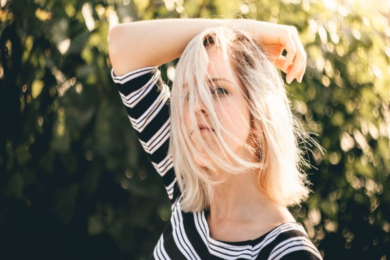 blonde woman in striped top standing near plant
