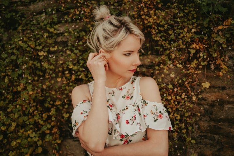 blonde woman in floral top standing near plants