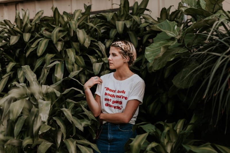 woman in white t-shirt standing near green plants