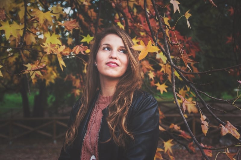 woman in black jacket standing near tree