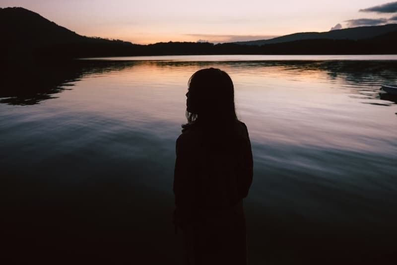 woman standing near water during sunset