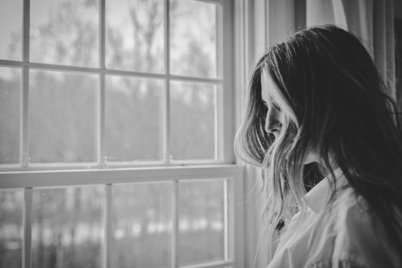 woman in white shirt standing near window