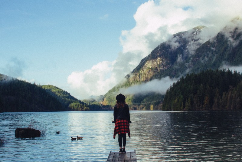 woman with hat standing on dock looking at water