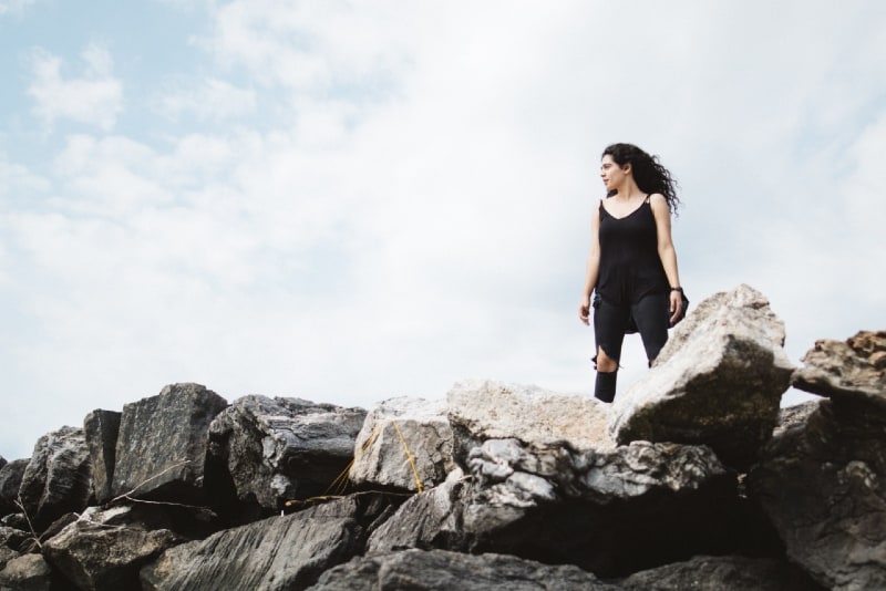 mujer con top negro de pie sobre las rocas