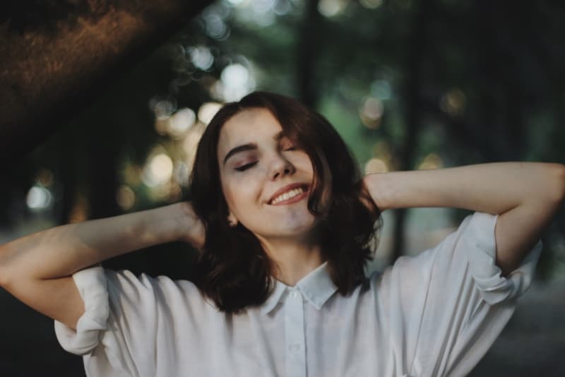 mujer sonriente con camisa blanca de pie al aire libre