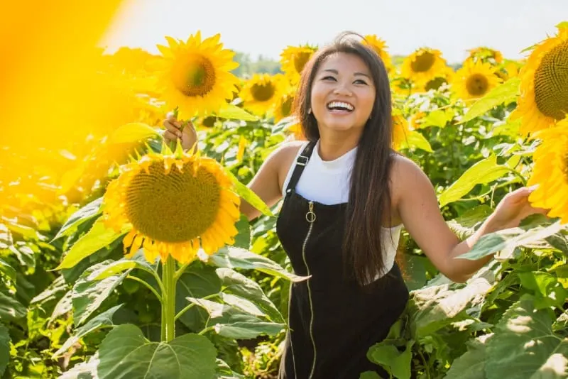 smiling woman standing surrounded sunflowers