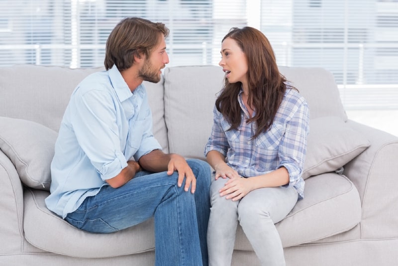 woman talking to man while sitting on sofa