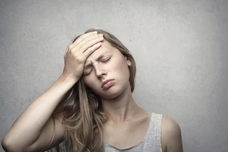 woman in gray top touching her forehead
