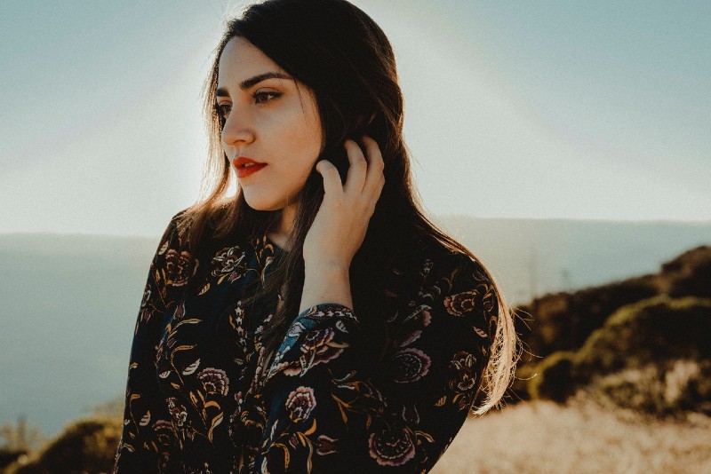 mulher com top floral a tocar no cabelo