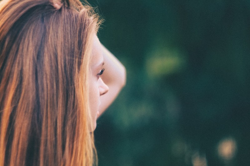 mulher a tocar no seu cabelo enquanto está ao ar livre