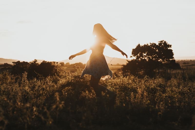woman turns around in field during sunrise/sunset in silhouette