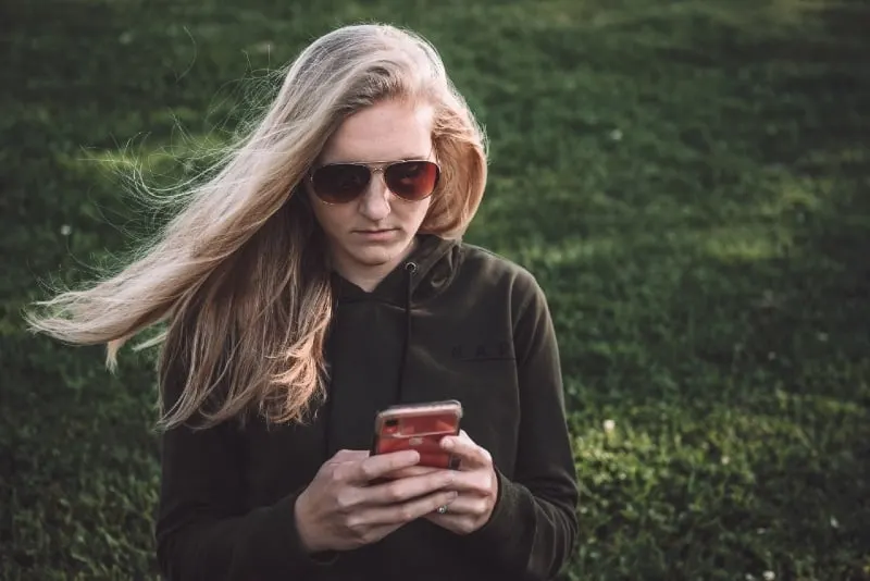 blonde woman with sunglasses using smartphone