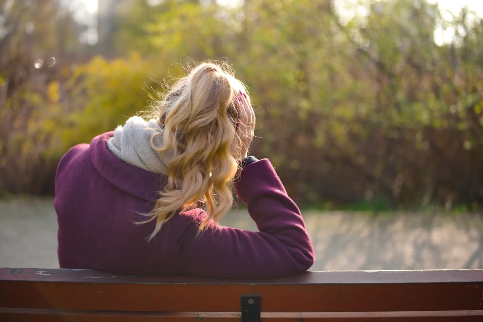 woman with blond hair sitting on a bench in the park