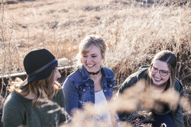 três mulheres sentadas ao ar livre e a conversar