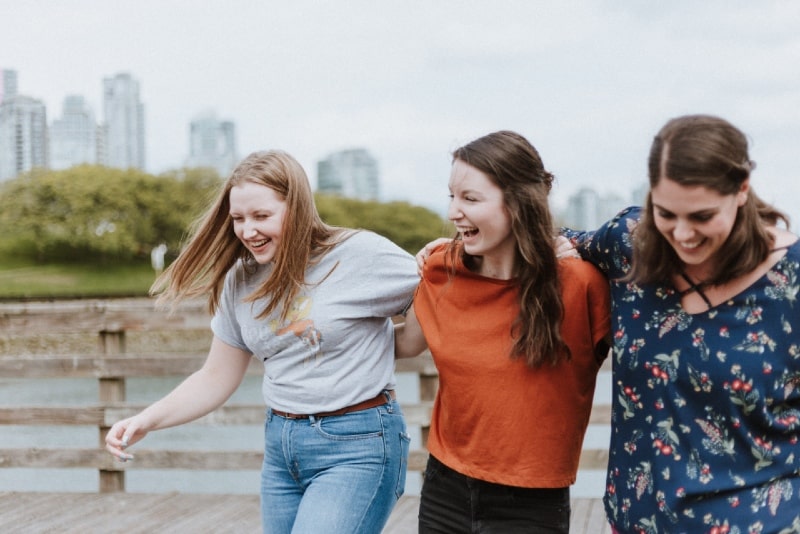 three women walking on dock near high rise buildings