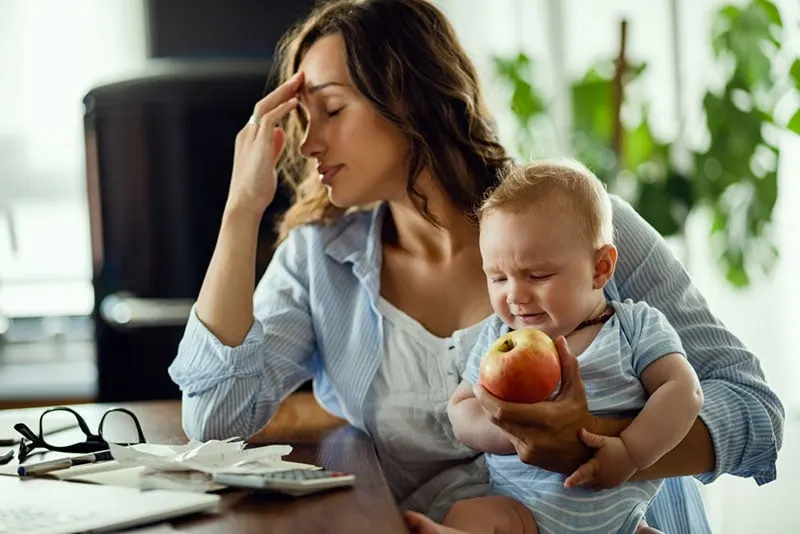 worried woman holding baby and an apple