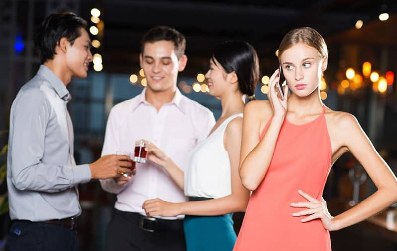 young woman on the phone during a party with 3 friends at her back toasting