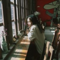 woman sitting at table near window