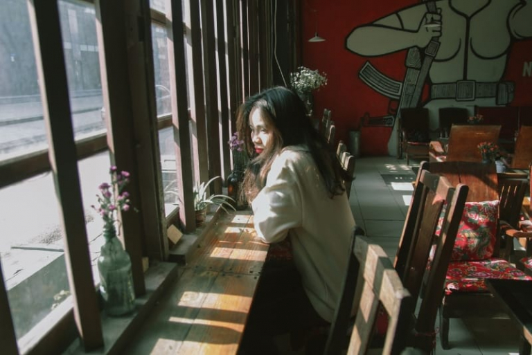 woman sitting at table near window
