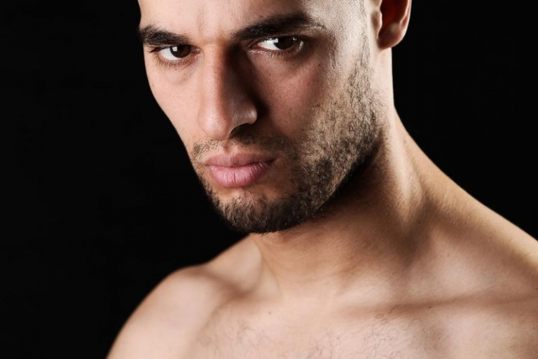 shirtless angry man standing in the dark with semi shaved beard