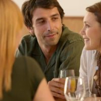 dos mujeres cenando con un hombre en primer plano