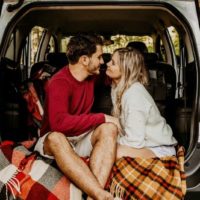 man and woman sitting on car's trunk