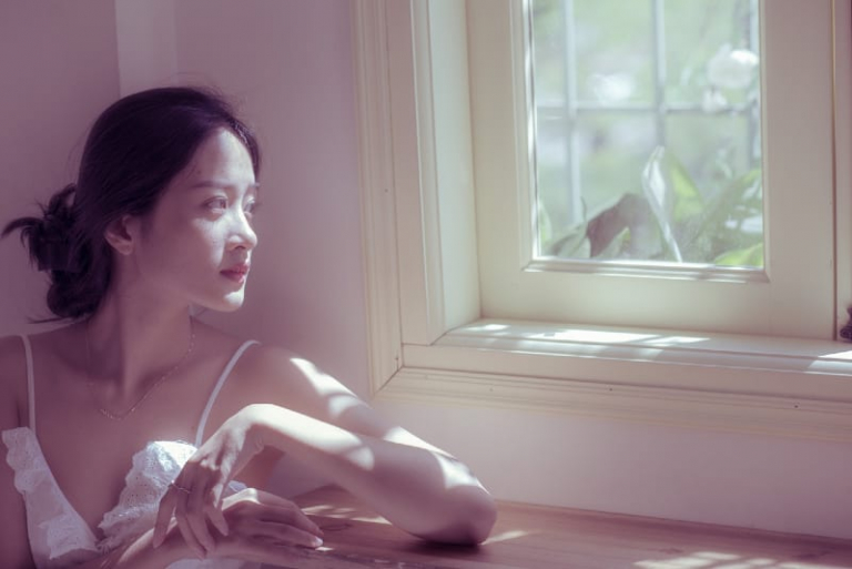 woman sitting at table looking through window