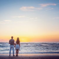 couple in love facing the sunset above the sea waters