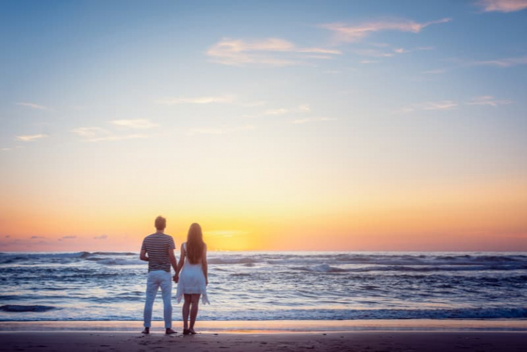 couple in love facing the sunset above the sea waters