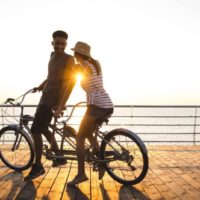 homem e mulher a andar de bicicleta durante o pôr do sol