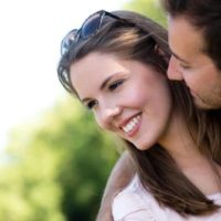 casal bonito homem a olhar e a tentar beijar a mulher a sorrir ao ar livre