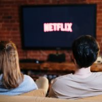 man and woman sitting on couch watching tv