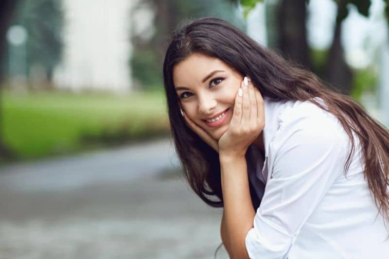 woman smiling outdoors sitting somewhere in the street of the city