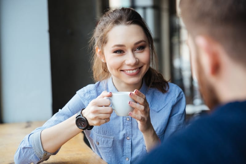 woman holding white mug looking at man