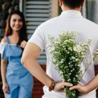 man holding flowers while standing in front of smiling woman