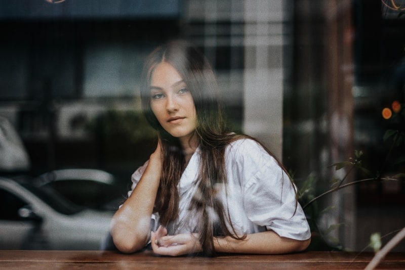 woman in white top leaning on table